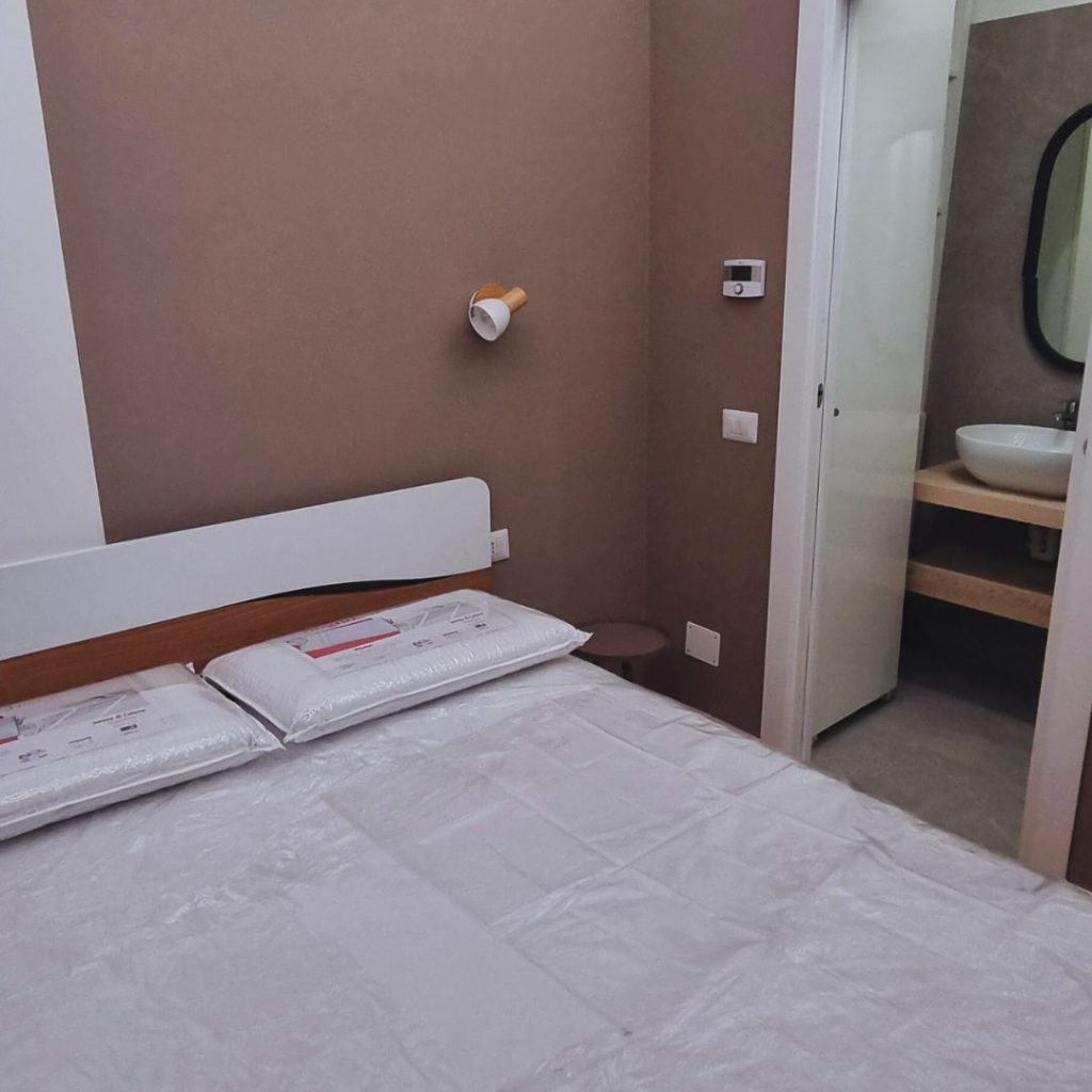 Monolocale 20 mq Milano Isola dopo ristrutturazione, arredamento zona notte con letto matrimoniale e accesso diretto al bagno.