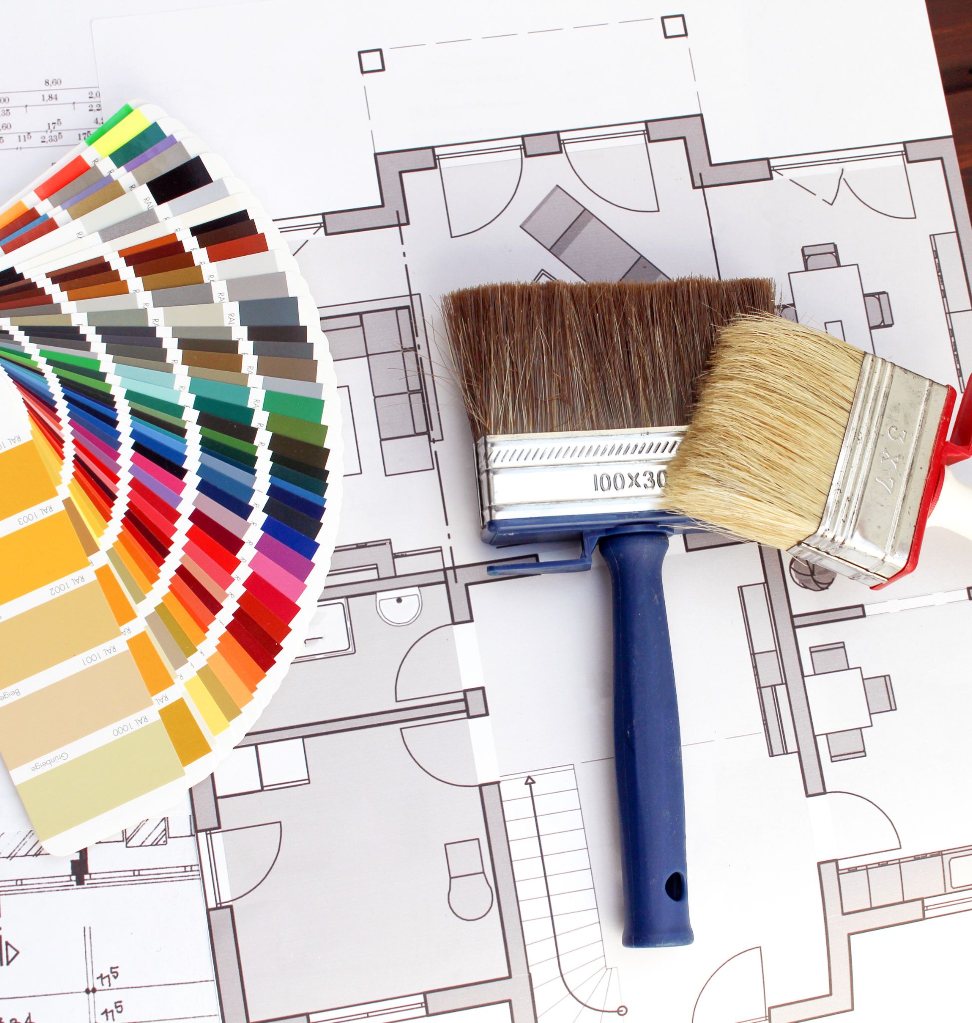 Mazzo di campioni di colore e due pennelli per pittura posati su un progetto dettagliato di ristrutturazione
