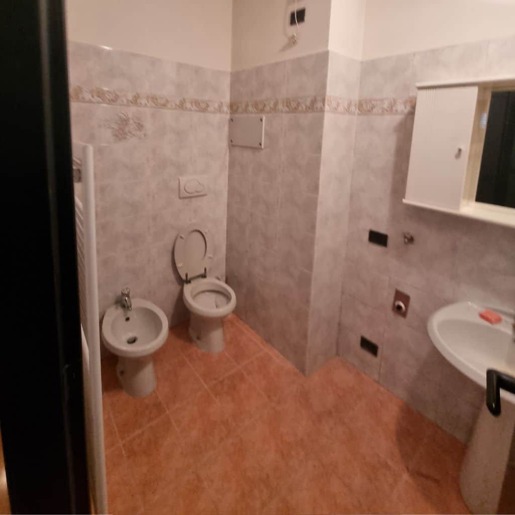 Bagno doccia prima (piastrelle grigie, pavimento arancio, sanitari tradizionali)