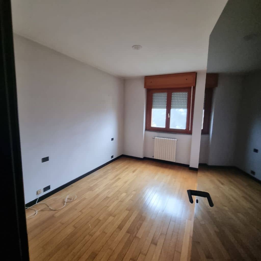 Camera matrimoniale prima della ristrutturazione con parquet originale e pareti neutre – zona Lorenteggio Milano