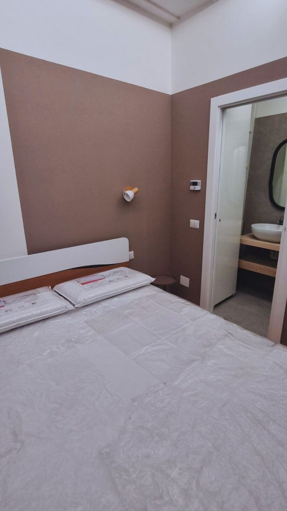 Monolocale 20 mq Milano Isola dopo ristrutturazione, arredamento zona notte con letto matrimoniale e accesso diretto al bagno.