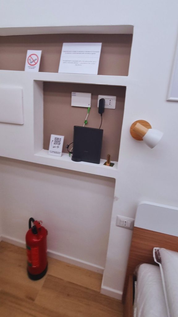Monolocale 20 mq ristrutturato in zona Isola a Milano, nicchia murale attrezzata con modem Wi-Fi, prese elettriche, QR code informativo e estintore a vista.