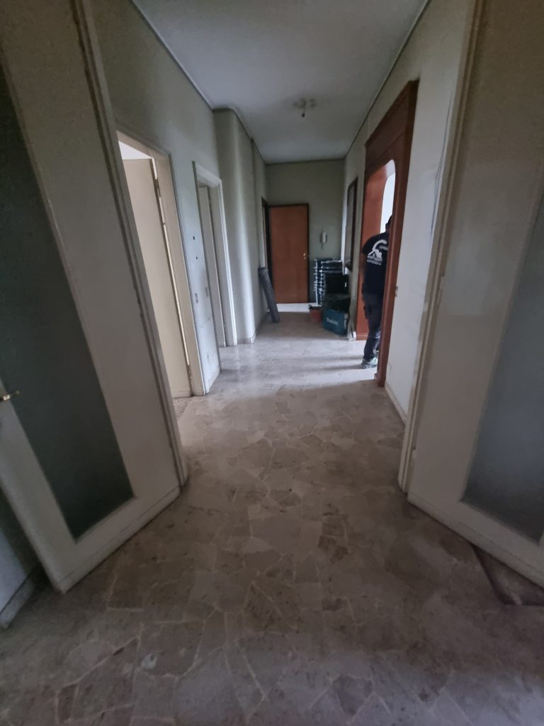 Corridoio con pavimento in marmo e porte vecchie, prima della ristrutturazione generale dell'appartamento a Milano Cenisio.