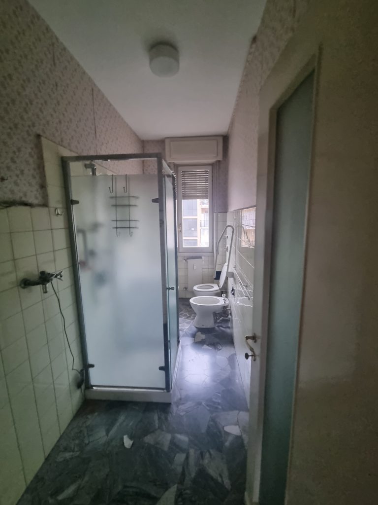 Bagno secondario obsoleto con rivestimenti datati e spazi ristretti, prima della ristrutturazione dell'appartamento a Milano Cenisio
