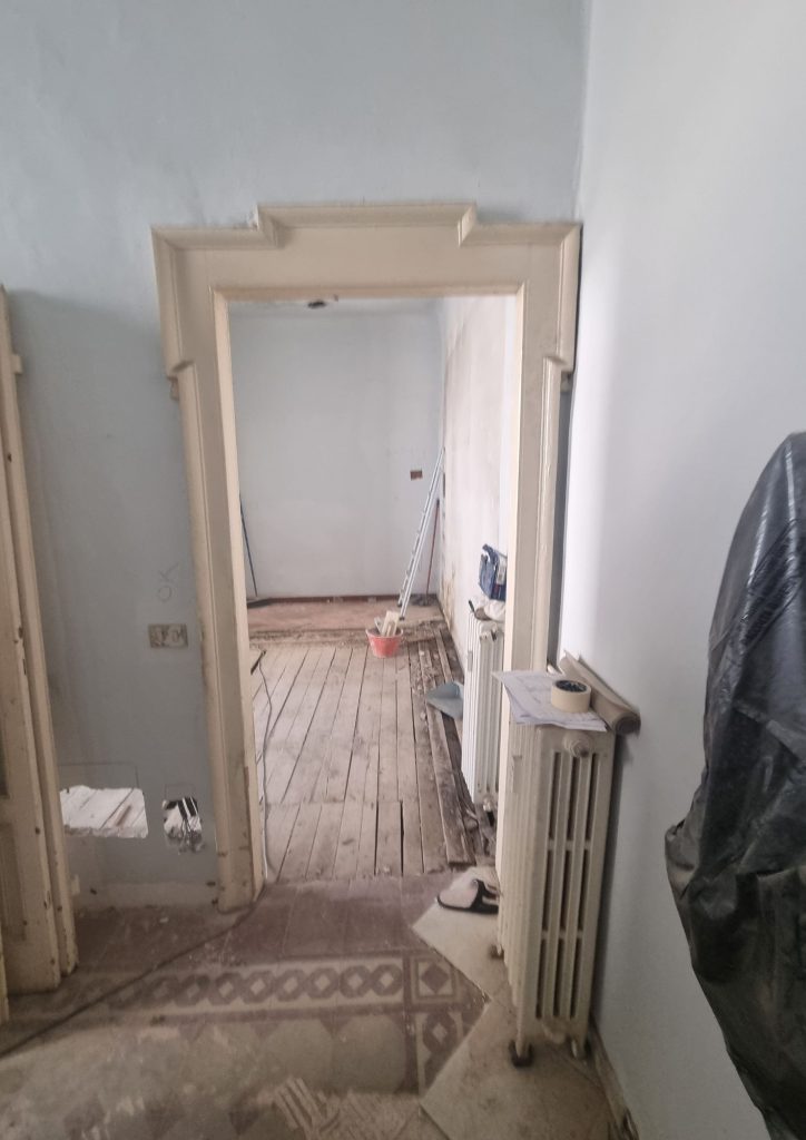 Bilocale 50 mq a Porta venezia Milano – corridoio prima della ristrutturazione con vecchio pavimento in legno e muri deteriorati