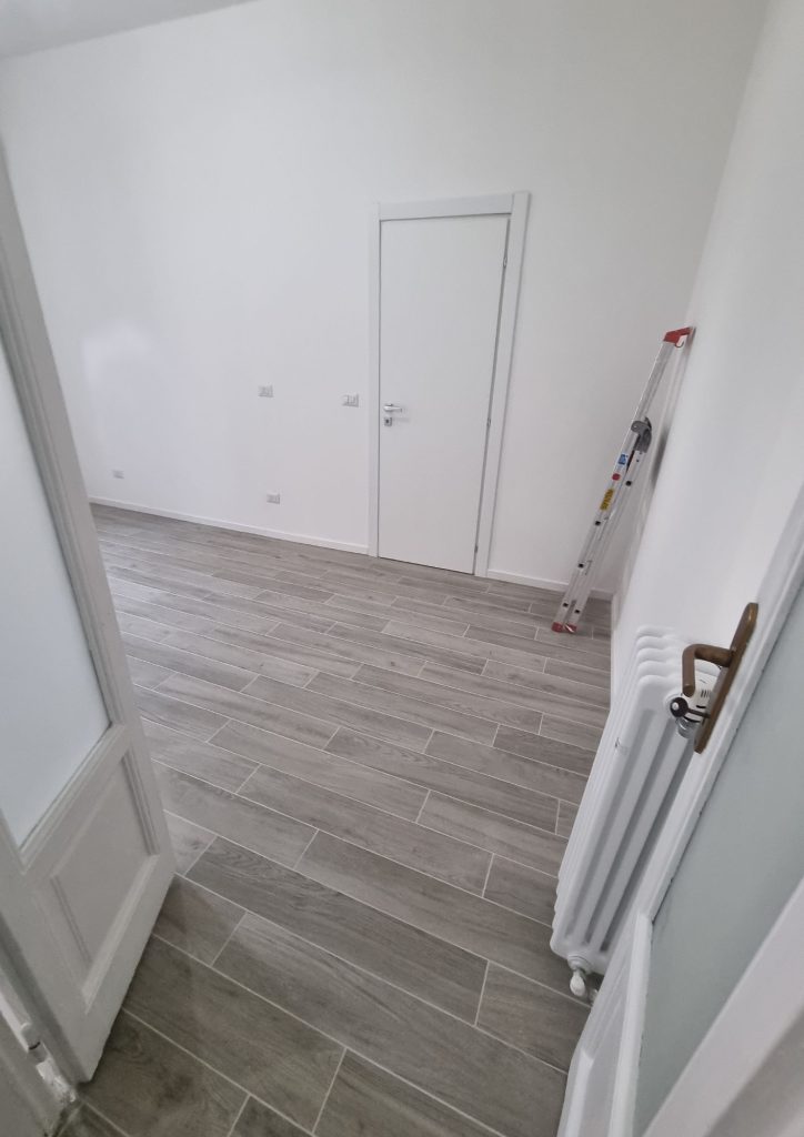 Bilocale 50 mq a Porta Venezia Milano – stanza ristrutturata con pavimento in gres effetto legno grigio e porte moderne bianche