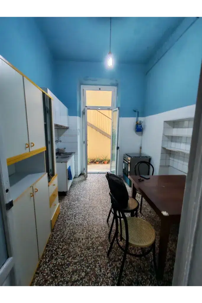 Cucina prima – arredi datati e pavimentazione graniglia con accesso esterno, trilocale 60 mq, bacone morgagni