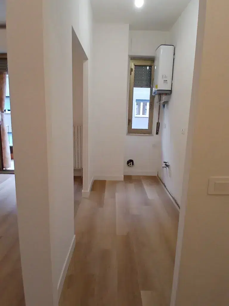 Cucina lineare ristrutturata con nuova distribuzione degli spazi, boiler installato e pavimento effetto legno coordinato con la zona giorno in bilocale a Milano Martesana