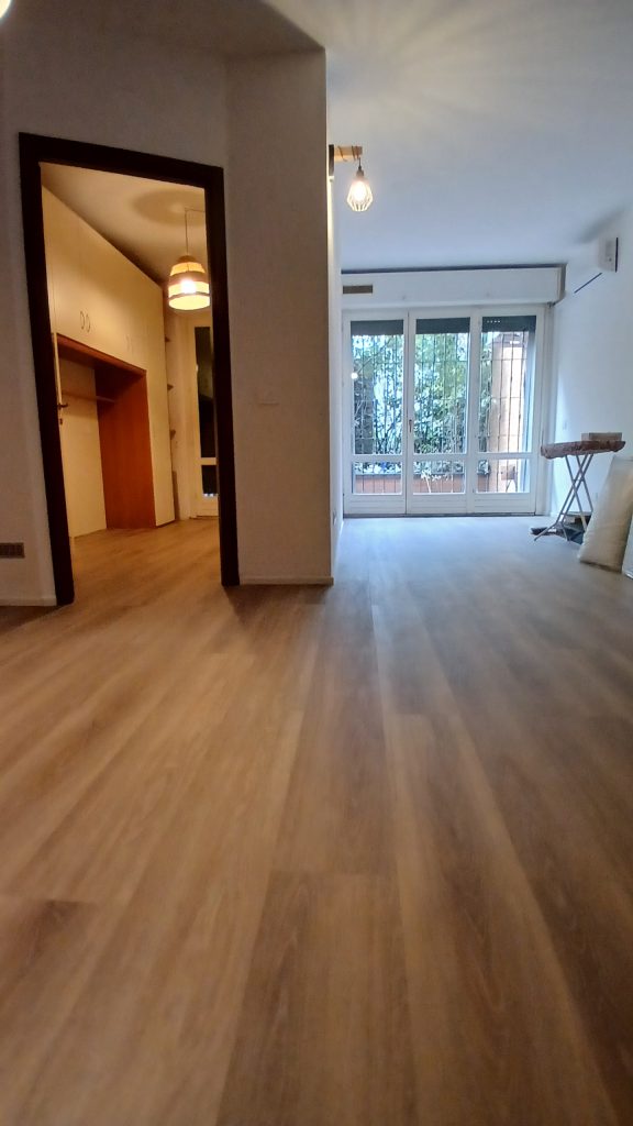 Soggiorno dopo – nuovo pavimento in laminato chiaro e pareti bianche, bilocale 40 mq, Romolo