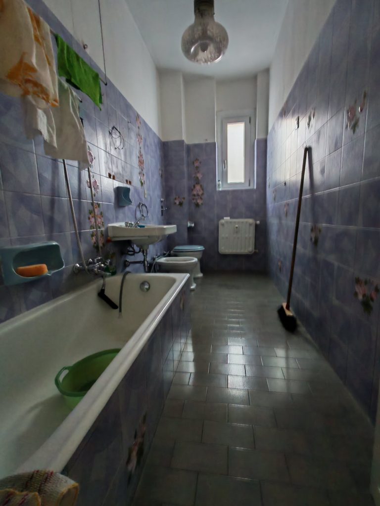 Bagno prima della ristrutturazione con piastrelle azzurre e sanitari datati – Gratosoglio Milano