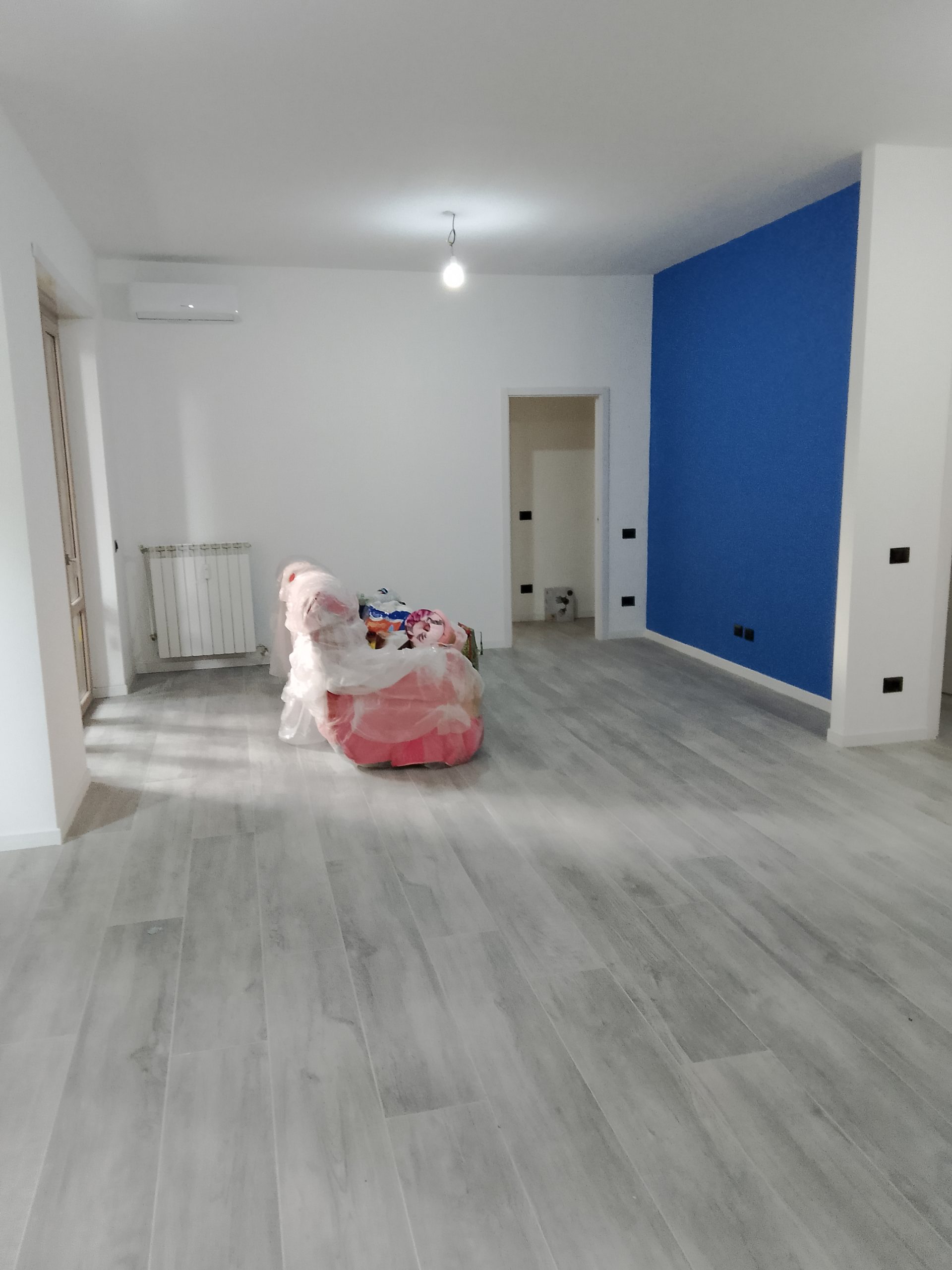 Soggiorno con parete d'accento in blu profondo, deep blue contrastante con pareti chiare e arredi neutri — appartamento 100 mq Bruzzano Milano