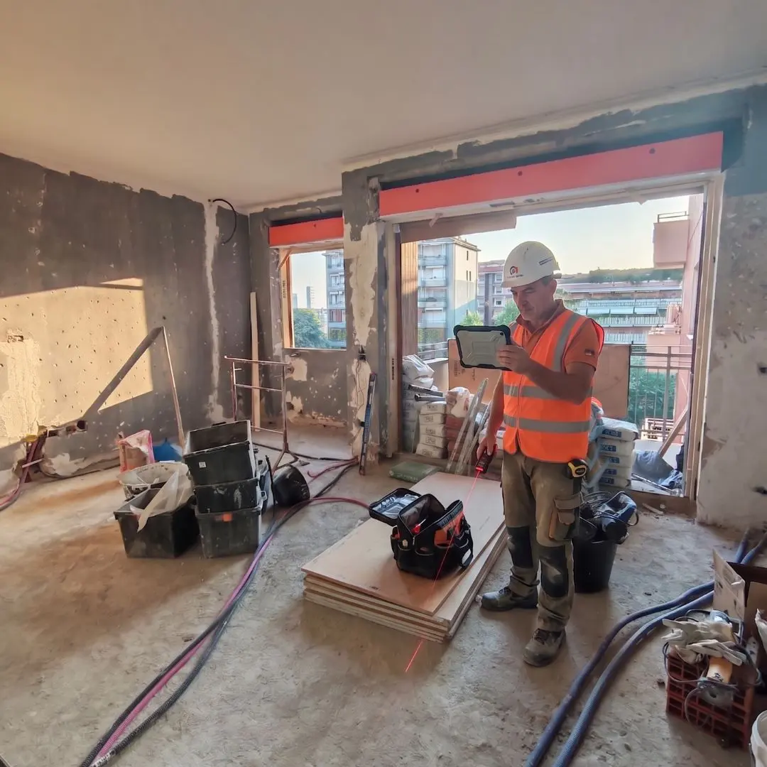Home 5 Tecnico di cantiere che effettua il rilievo dello stato avanzamento dei lavori con tablet in un appartamento in ristrutturazione.